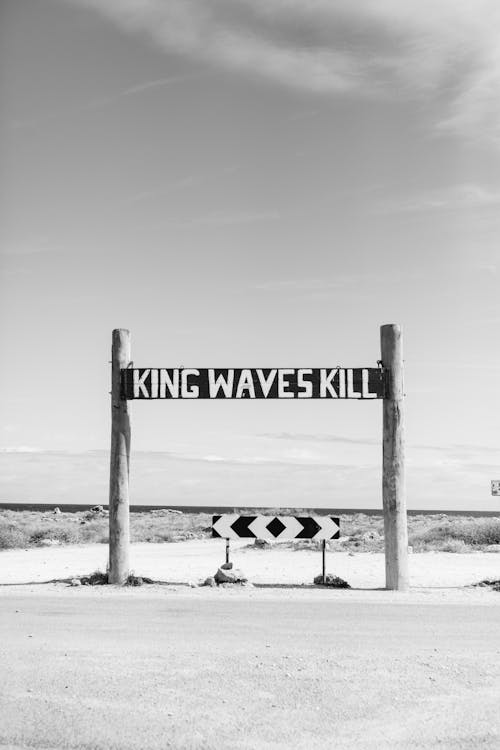 Black and white of king waves kill sign warning of danger of sea storm located near road