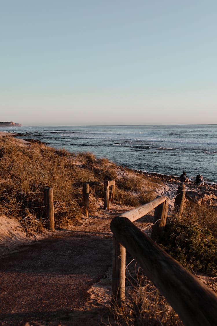 Walkway With Wooden Fence Leading To Sea