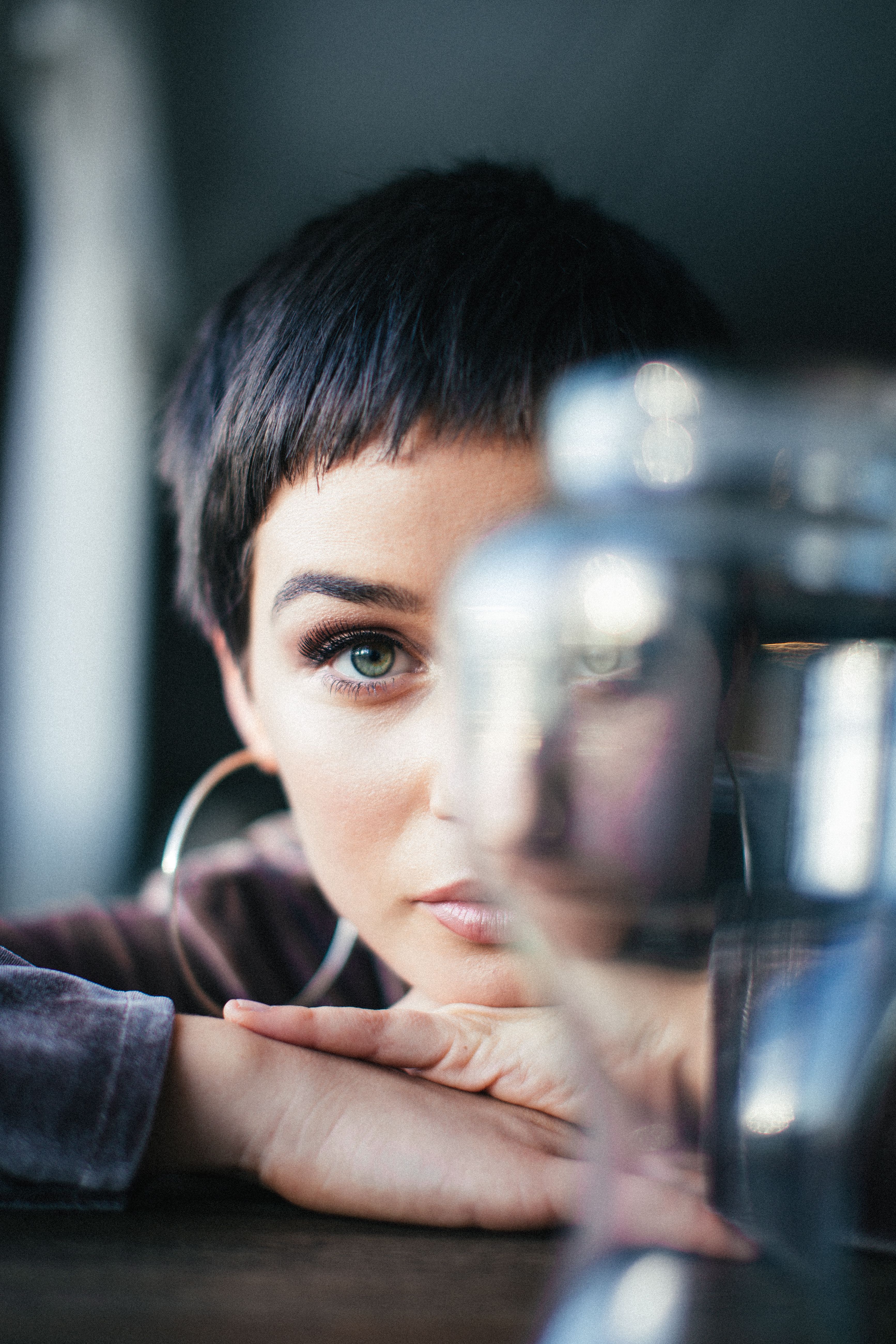 Artistic portrait of a woman with short hair and hoop earrings gazing confidently.