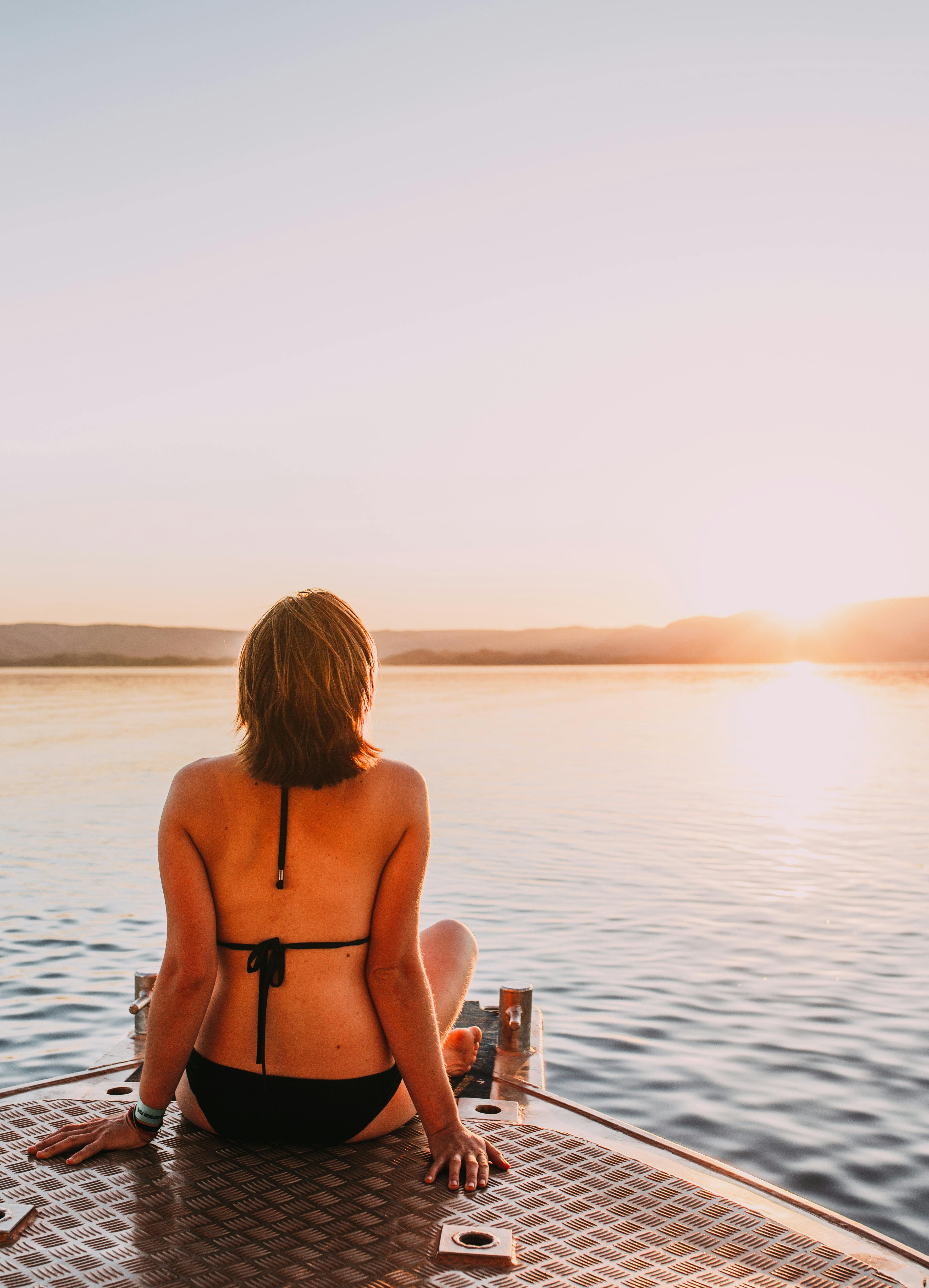 一个女人坐在湖边的码头上，享受着日落时分的宁静