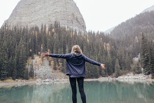 Woman with arms outstretched standing on coast of lake