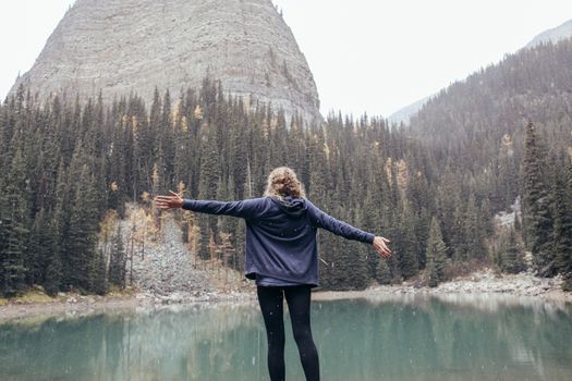 一个女人在宁静的山湖上张开双臂，享受自由