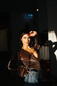 一位自信的短发年轻女性手扶额头，站在阳光下看着镜头