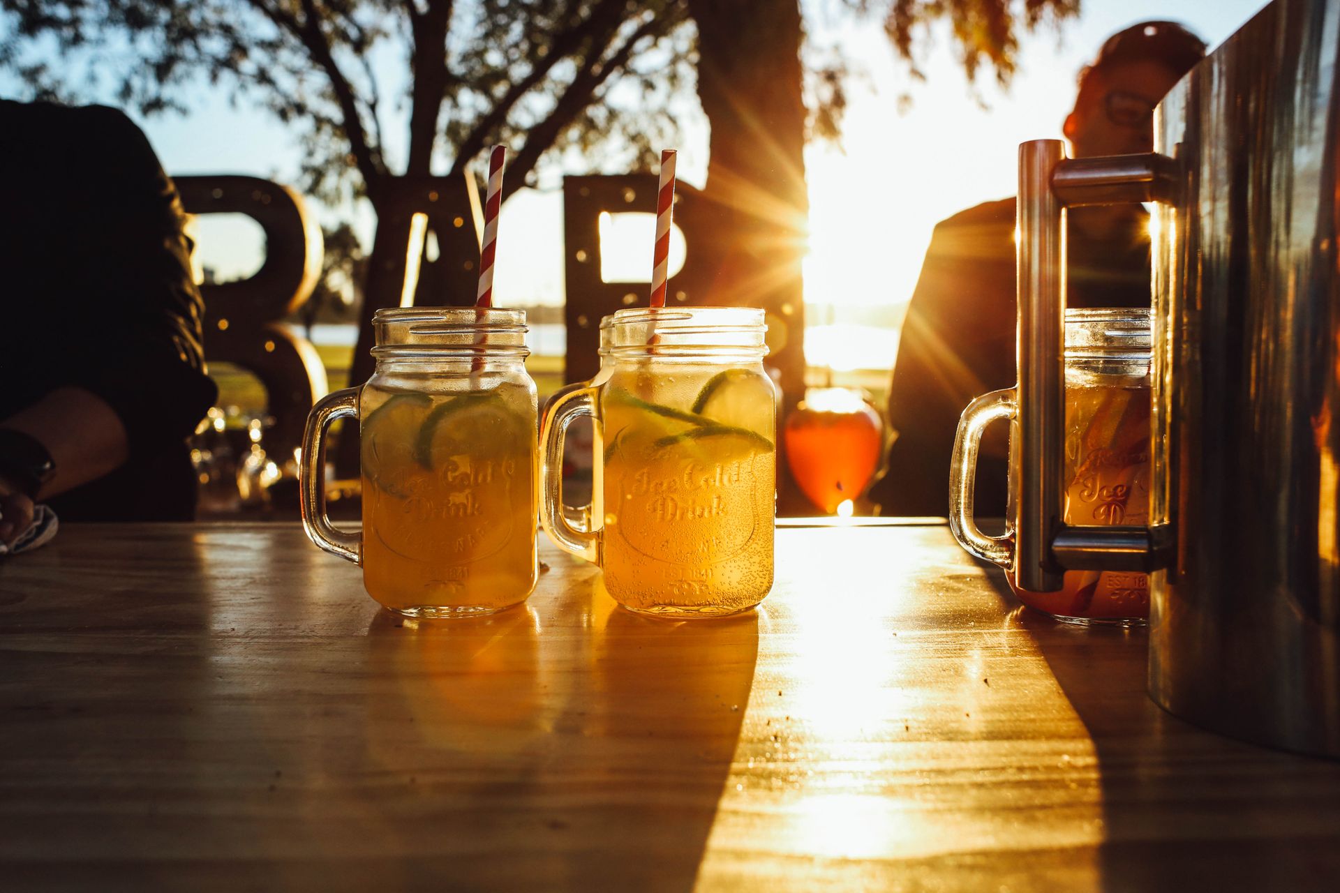 Two glasses of citrus lemonade with lime on a table at sunset, perfect refreshment for sunny days.
