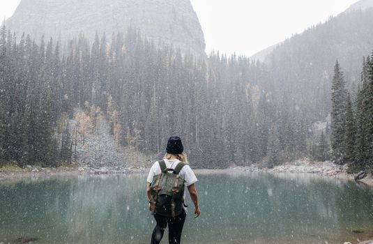 冒险者徒步穿越积雪的森林，抵达了平静的山湖