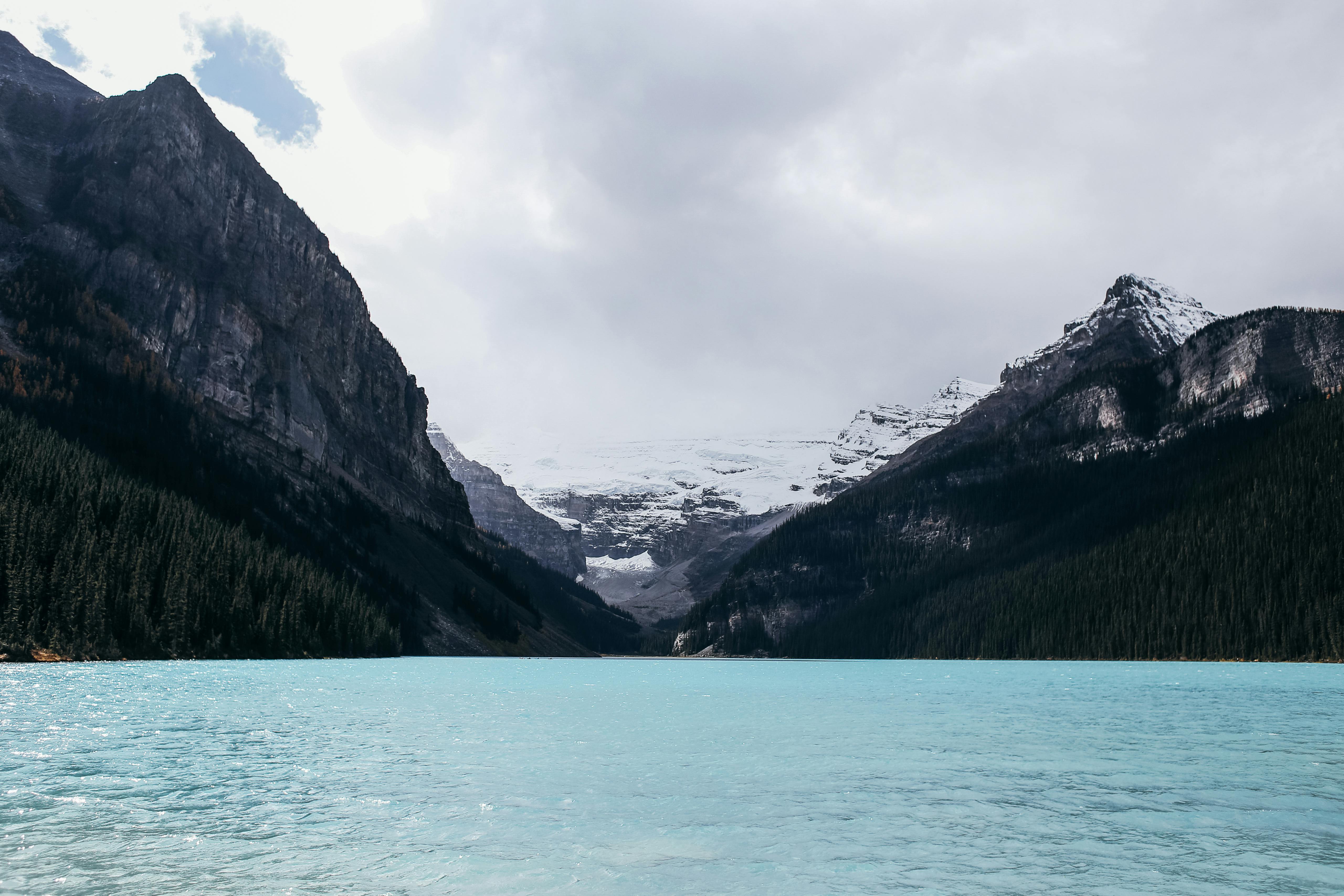 Calm rippling blue lake surrounded by mountains and forest · Free Stock