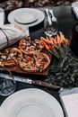 High angle of cut pies on wooden cutting board near bread and carrot near plates wineglasses and knife