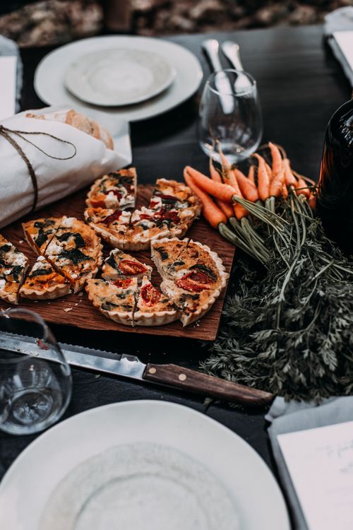 Free High angle of cut pies on wooden cutting board near bread and carrot near plates wineglasses and knife Stock Photo