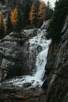 风景如画的瀑布从森林中岩石上层层流下，四周环绕着秋天的树叶