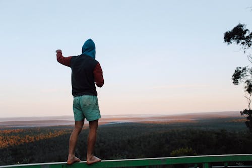 Unrecognizable man standing on railing over woodland