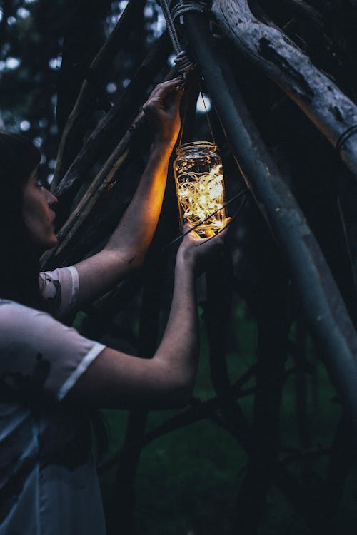 Crop woman with decorative lamp near wooden structure