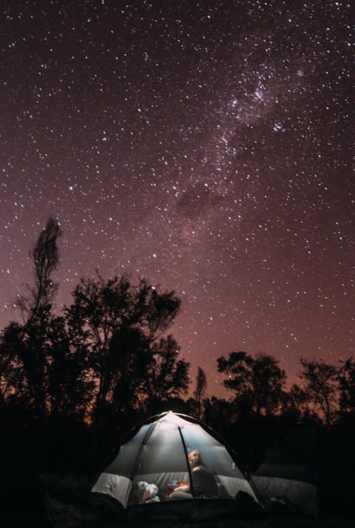 Anonymous camper in tent against starry sky