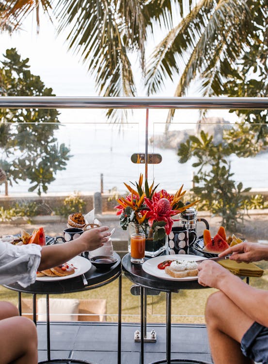 Unrecognizable young couple having breakfast on terrace during romantic trip
