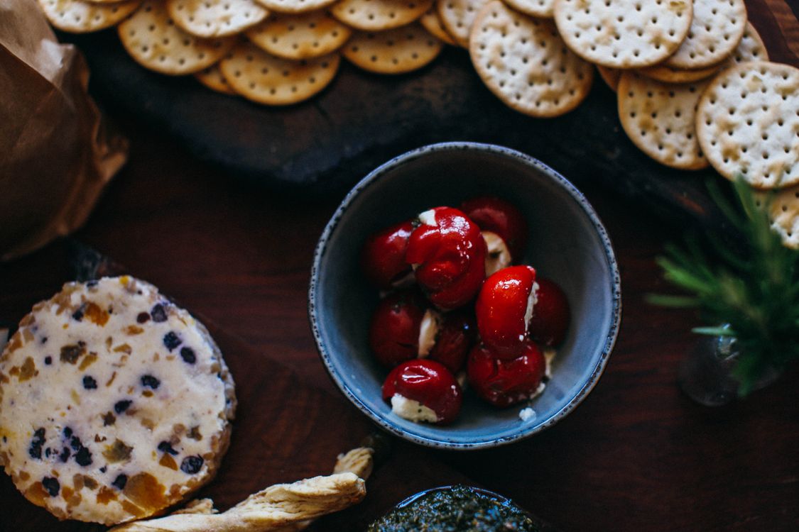 Stuffed cherry peppers with soft cheese and crackers on a table