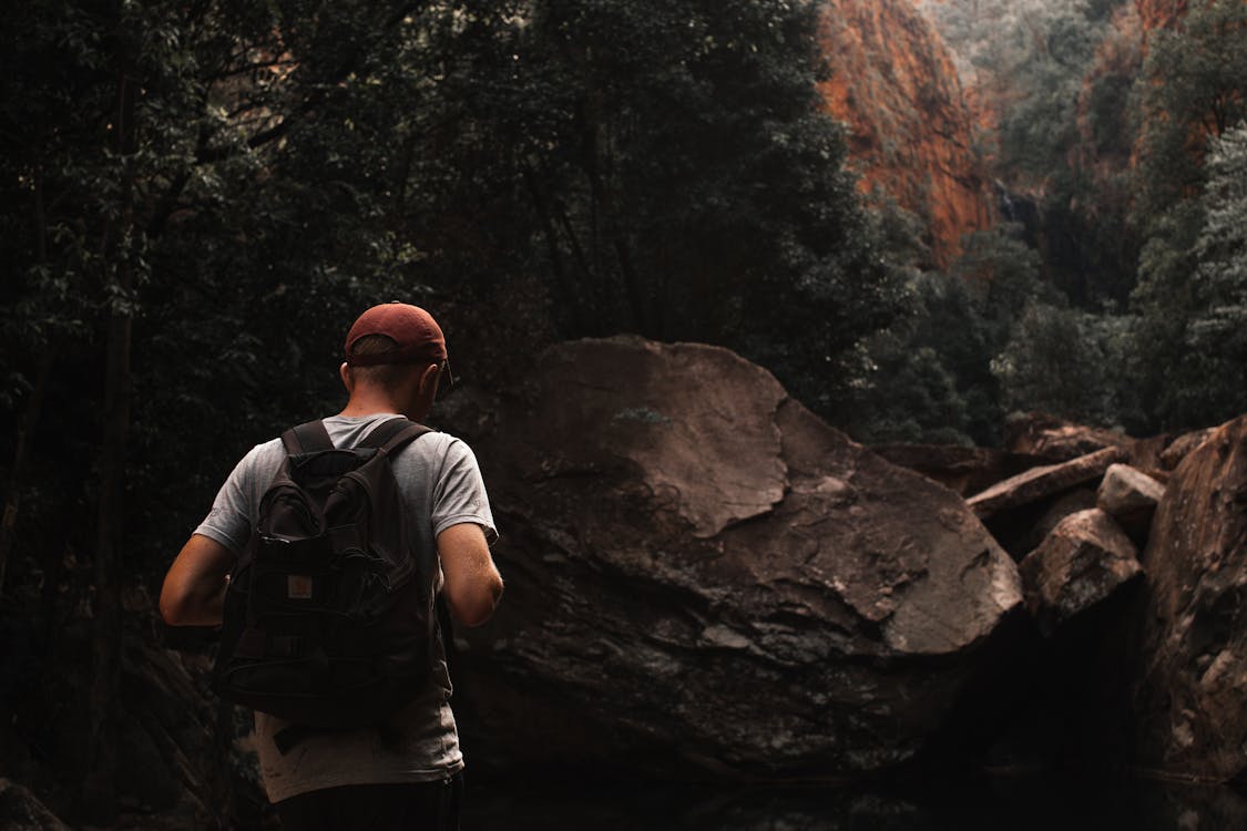 Free Anonymous male backpacker exploring rocky mountains during hiking trip Stock Photo