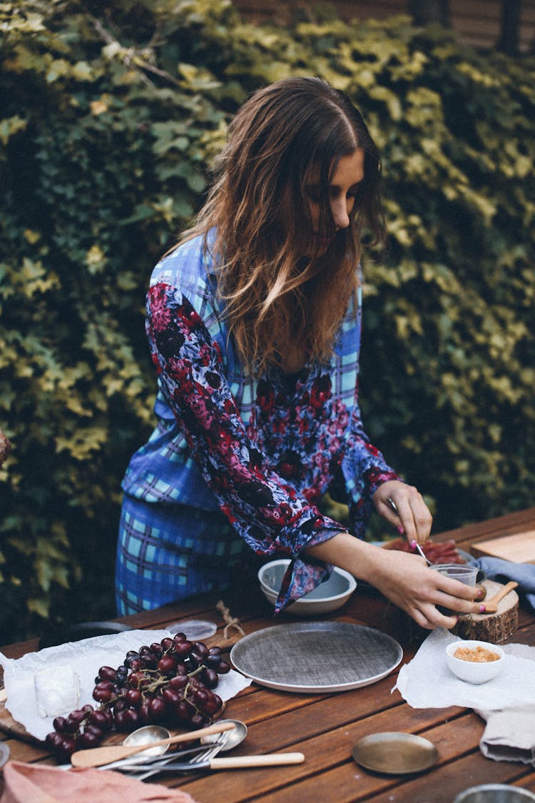 Young Woman Setting Table For Lunch In Garden