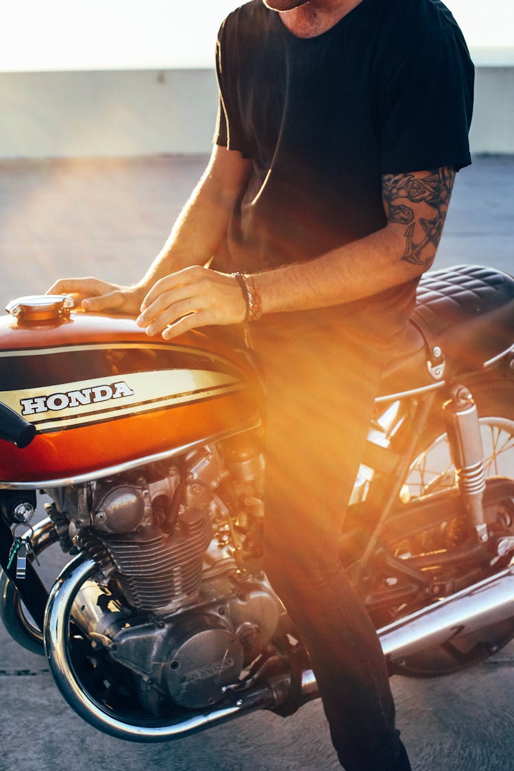 Crop Tattooed Guy Sitting On Motorbike At Sunset