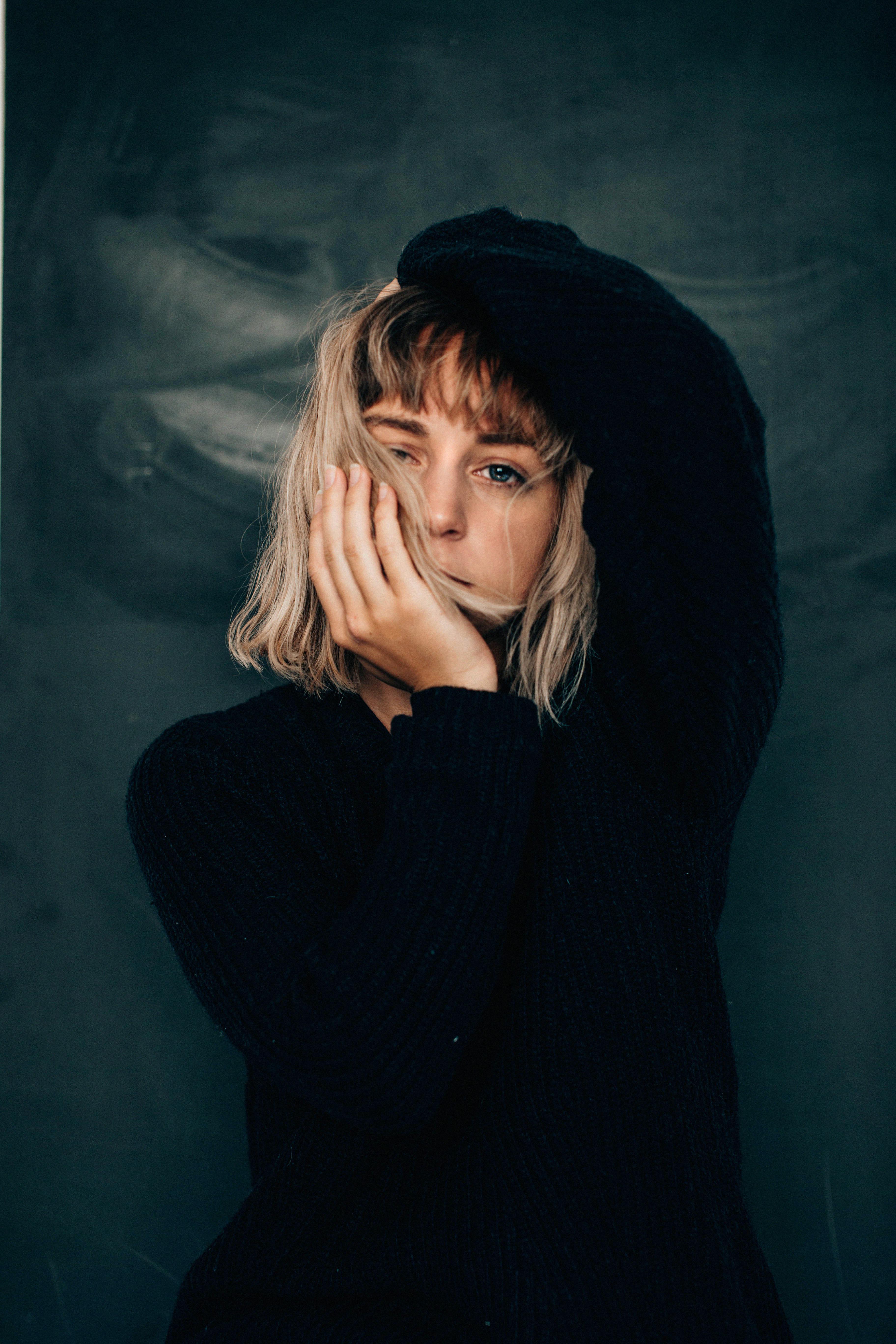 thoughtful young woman touching face and looking at camera in studio