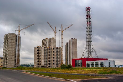 High-rise buildings and cranes at an urban construction site under a cloudy sky.