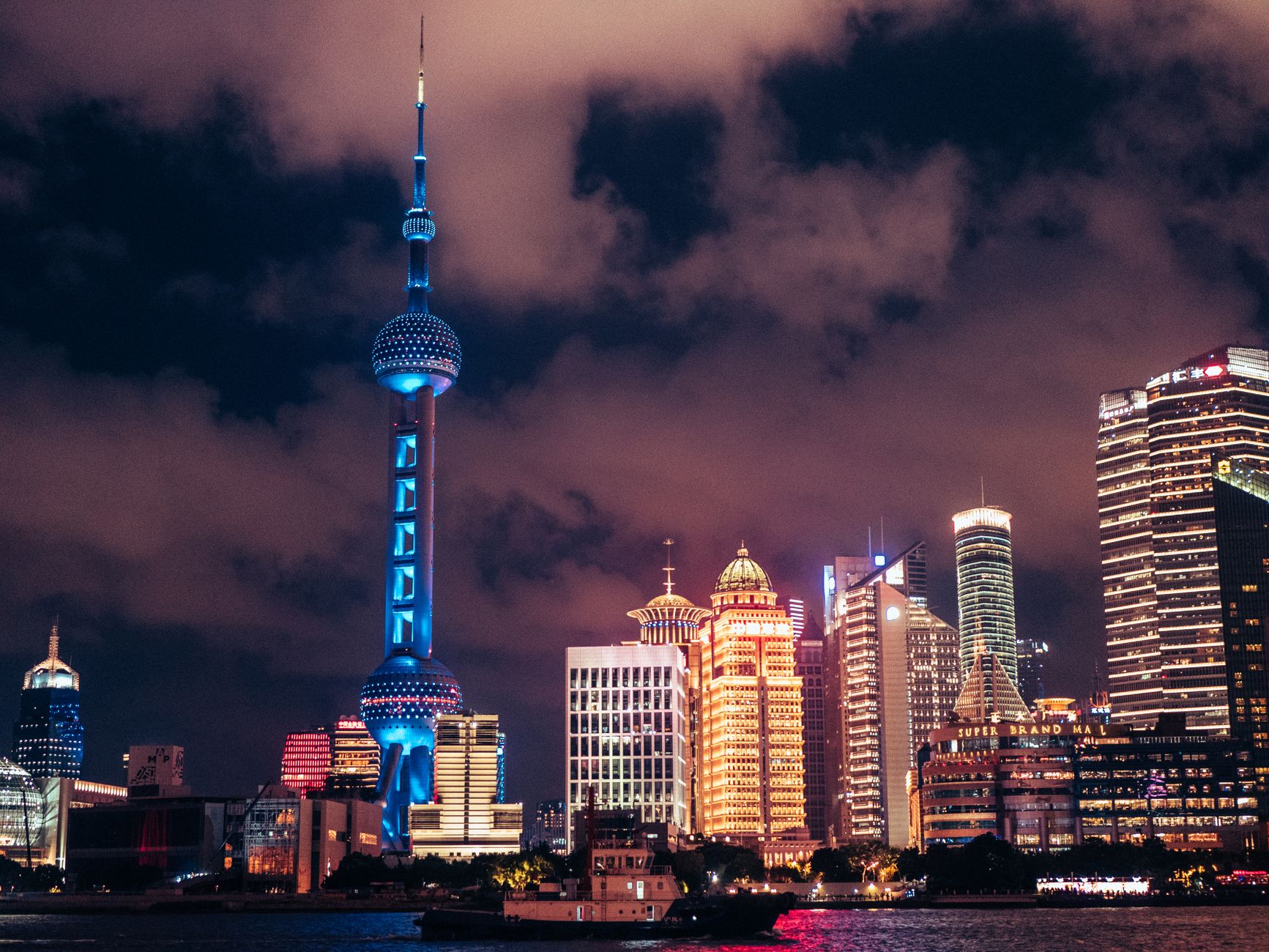 Night view of Shanghai skyline with illuminated Oriental Pearl Tower and city lights.