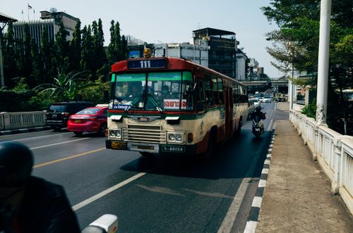 Free Busy Bangkok street scene featuring a classic public bus and motorbike bustling through traffic. Stock Photo