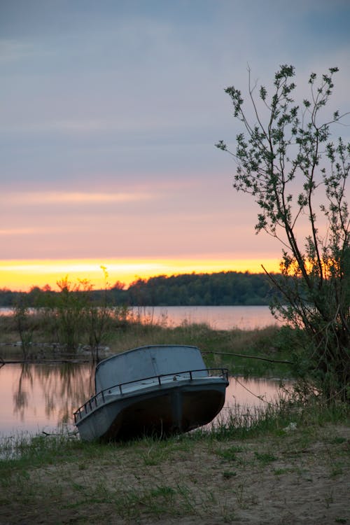 White Motorboat Docked on Side of Lake during Sunset