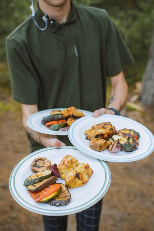 Person in Green Shirt Holding Three White Ceramic Plates With Food