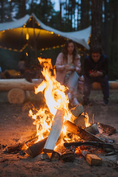 Free Two people enjoy a warm campfire surrounded by nature in a forest setting. Stock Photo