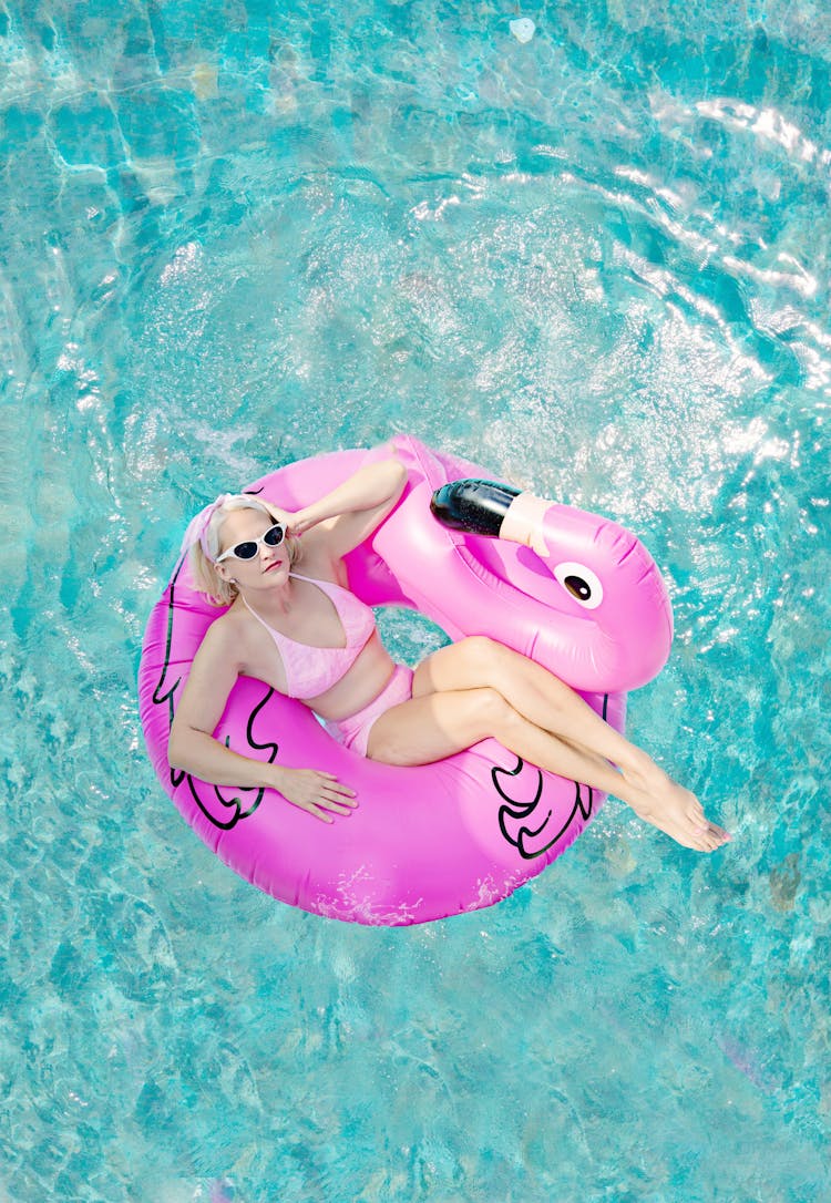 A Woman In Pink Bikini Lying On Pink Inflatable Float On Pool