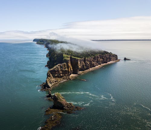 Rock in mist on sea under cloudy sky