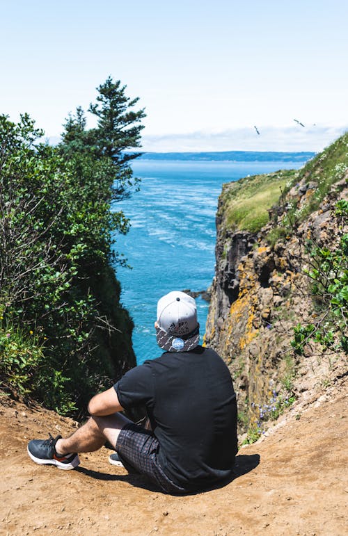 Anonymous male traveler contemplating sea from mount