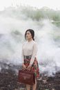 一名年轻的亚洲女子穿着时髦，在朦胧的户外环境中沉思地站着