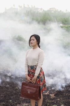 一名年轻的亚洲女子穿着时髦，在朦胧的户外环境中沉思地站着