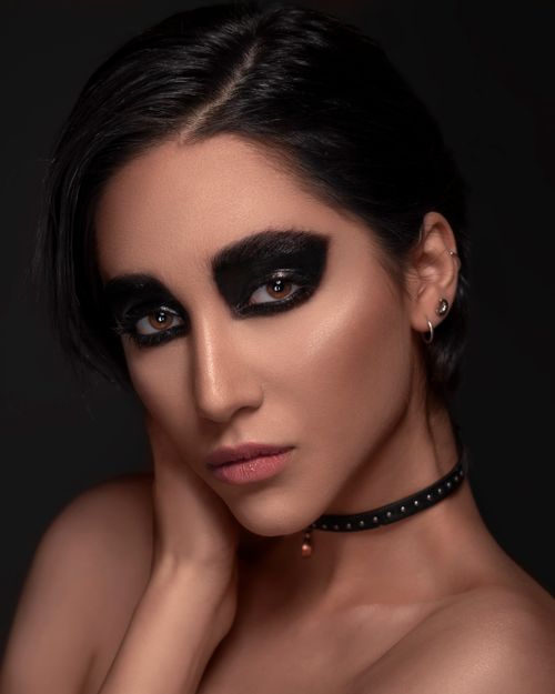 Free Close-up portrait of a woman with intense black eyeshadow and short hair against a dark background. Stock Photo