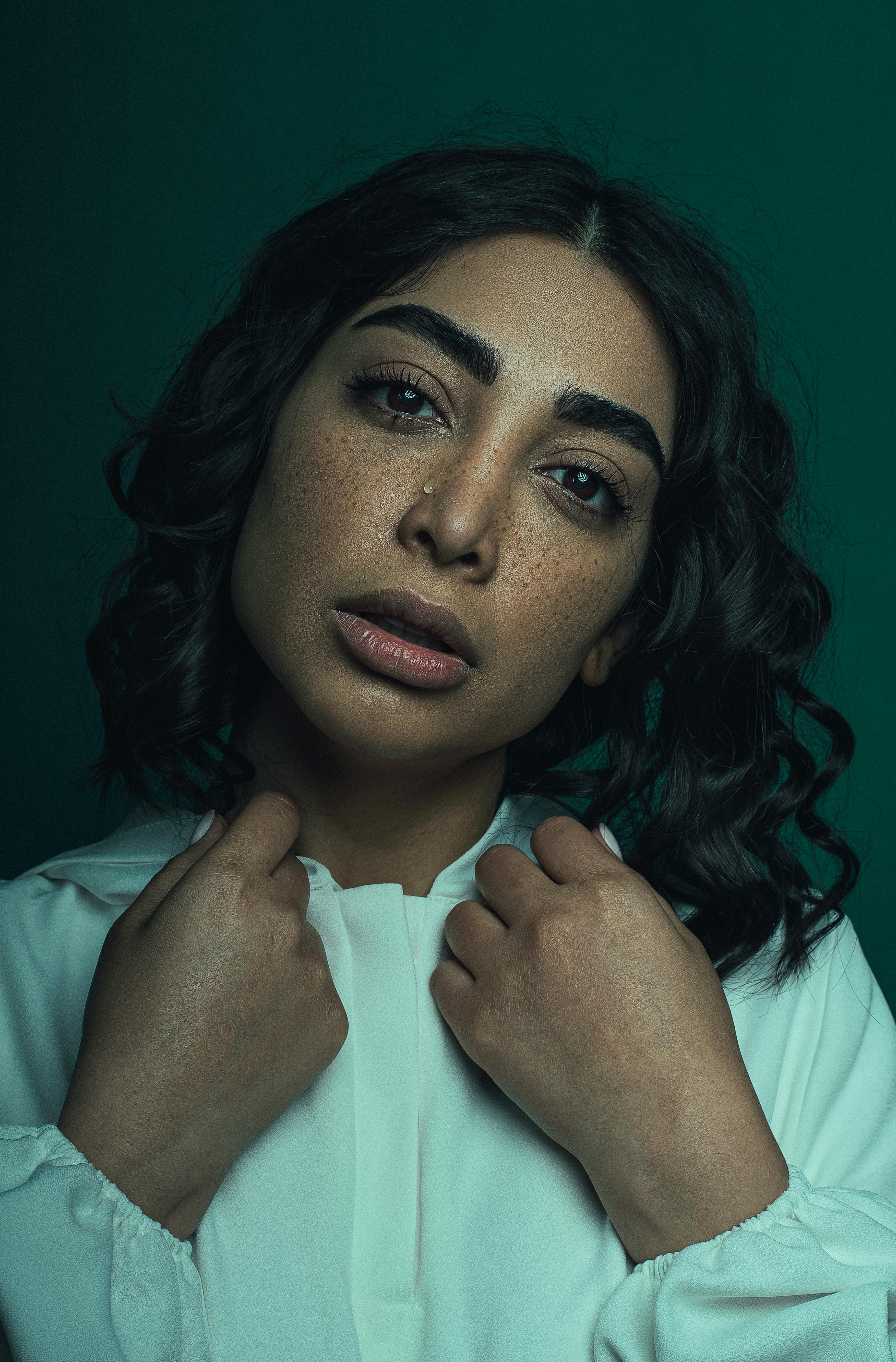 An intimate studio portrait showcasing a woman with curly hair and freckles, capturing a serious expression in New York.