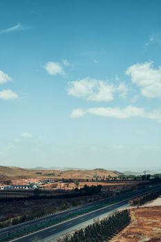 Aerial view of a countryside road in Hohhot, Inner Mongolia, China under a clear blue sky.