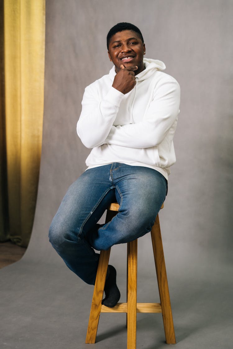 Man In A White Hoodie Sitting On A Wooden Stool