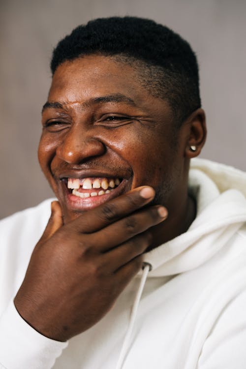 Free Portrait of a Man in a White Top Smiling while His Hand is on His Chin Stock Photo