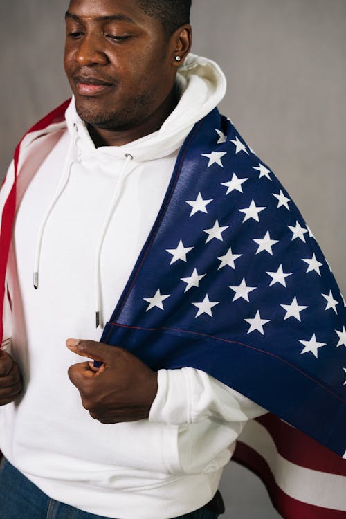 Man in a White Hoodie Holding a United States of America Flag on His Back