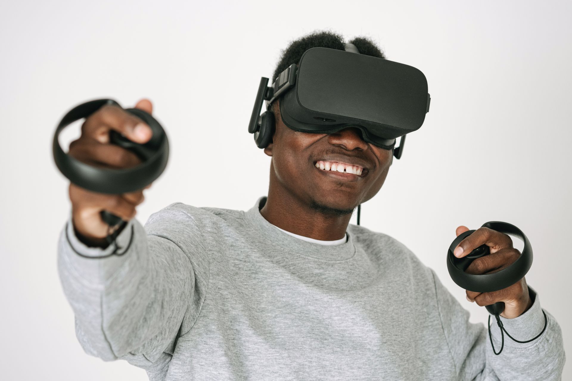 A man wearing a VR headset and controllers is smiling and enjoying a virtual reality experience indoors.