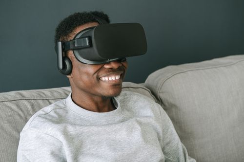 Free A happy man wearing VR glasses relaxes on a couch, enjoying a virtual reality experience. Stock Photo