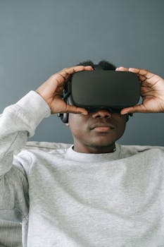 A focused man in a gray sweater immersed in virtual reality using a VR headset.