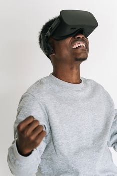 A cheerful adult enjoying a virtual reality experience indoors wearing a VR headset.
