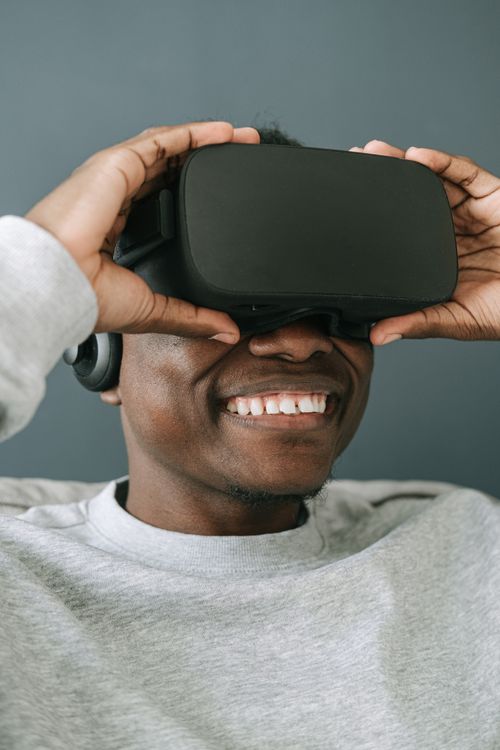 Free A smiling man enjoys a virtual reality experience using a VR headset indoors. Stock Photo