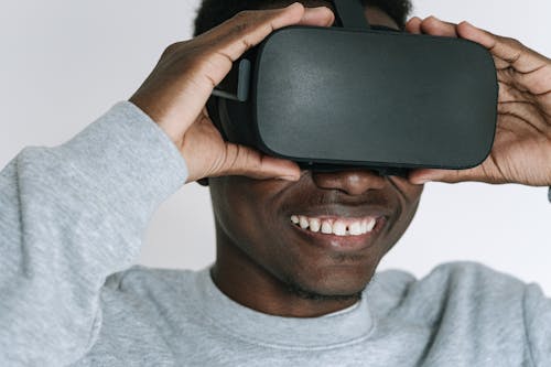 Man in Gray Sweater Holding Virtual Reality Headset