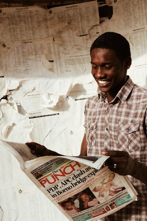 Laughing black man reading newspaper