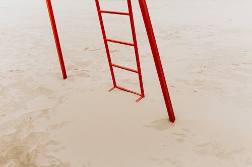 Red Wooden Ladder on a Sandy Shore