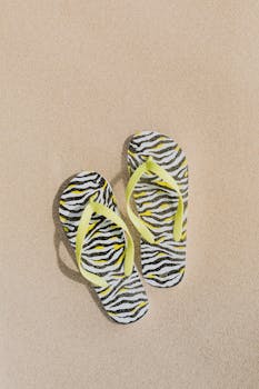 这款时尚的斑马印花人字拖，在沙滩上搭配着黄色肩带