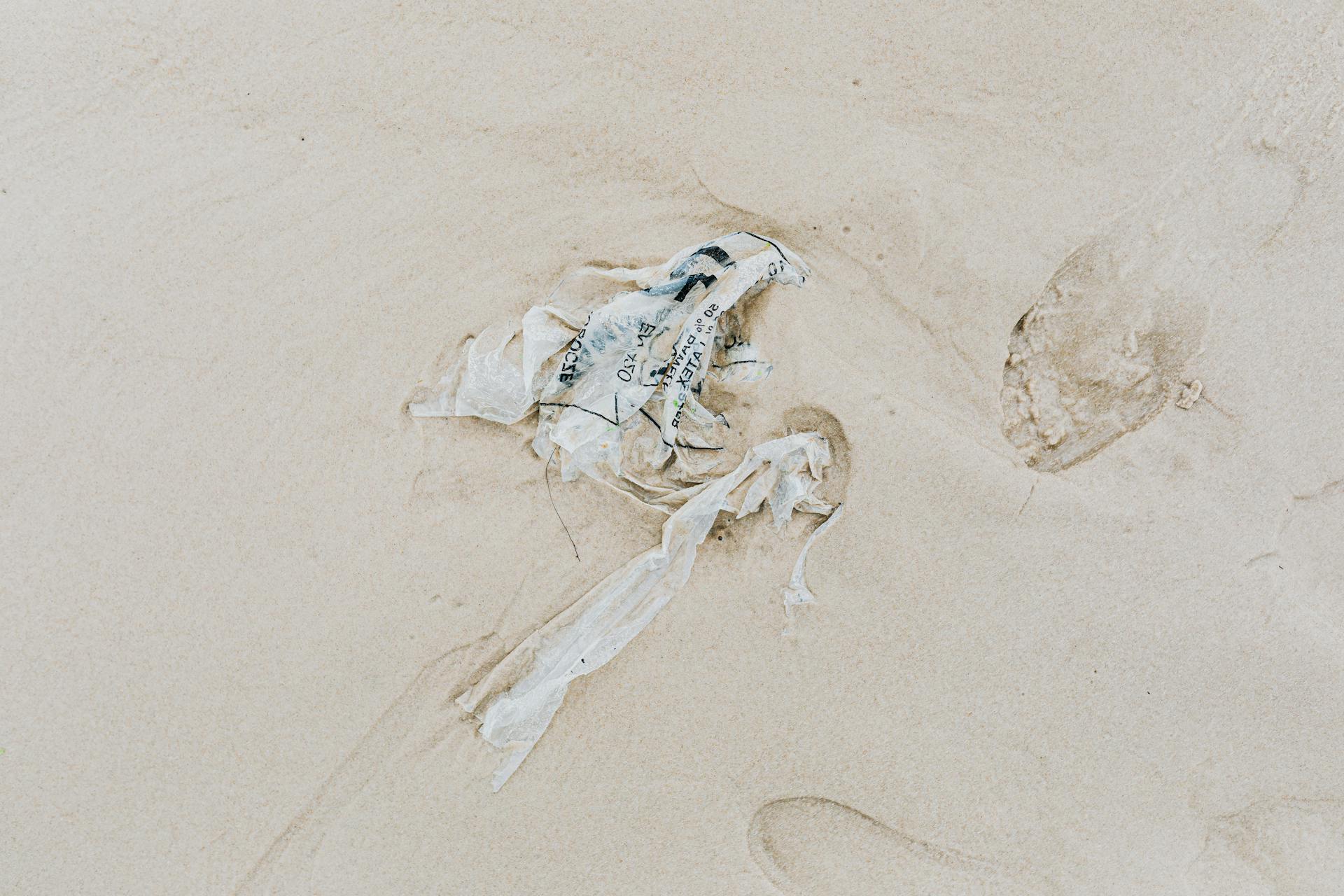 Plastic Trash on the Sandy Shore Beside Footprints