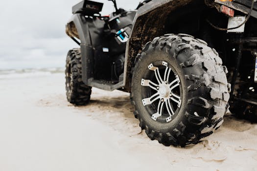 Close-up of an ATV tire on a sandy beach, showcasing rugged design and adventure capability.
